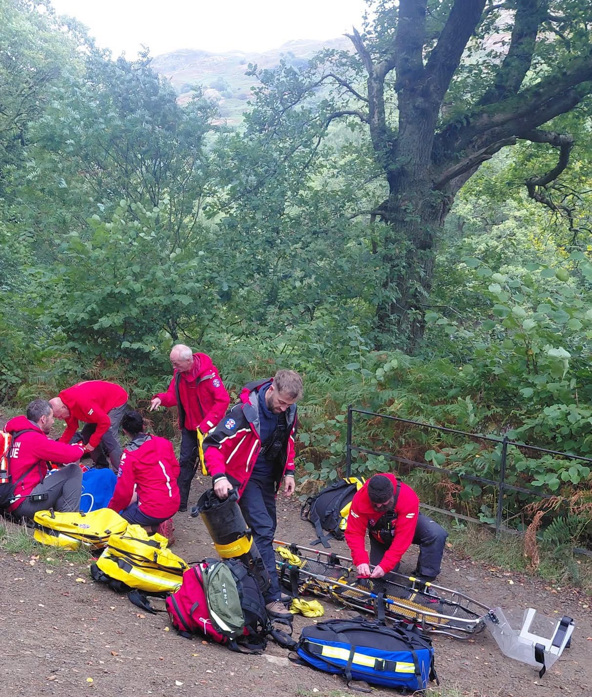 Patterdale Mountain Rescue Team members assembling a stretcher and preparing equipment on a wooded path at Aira Force.