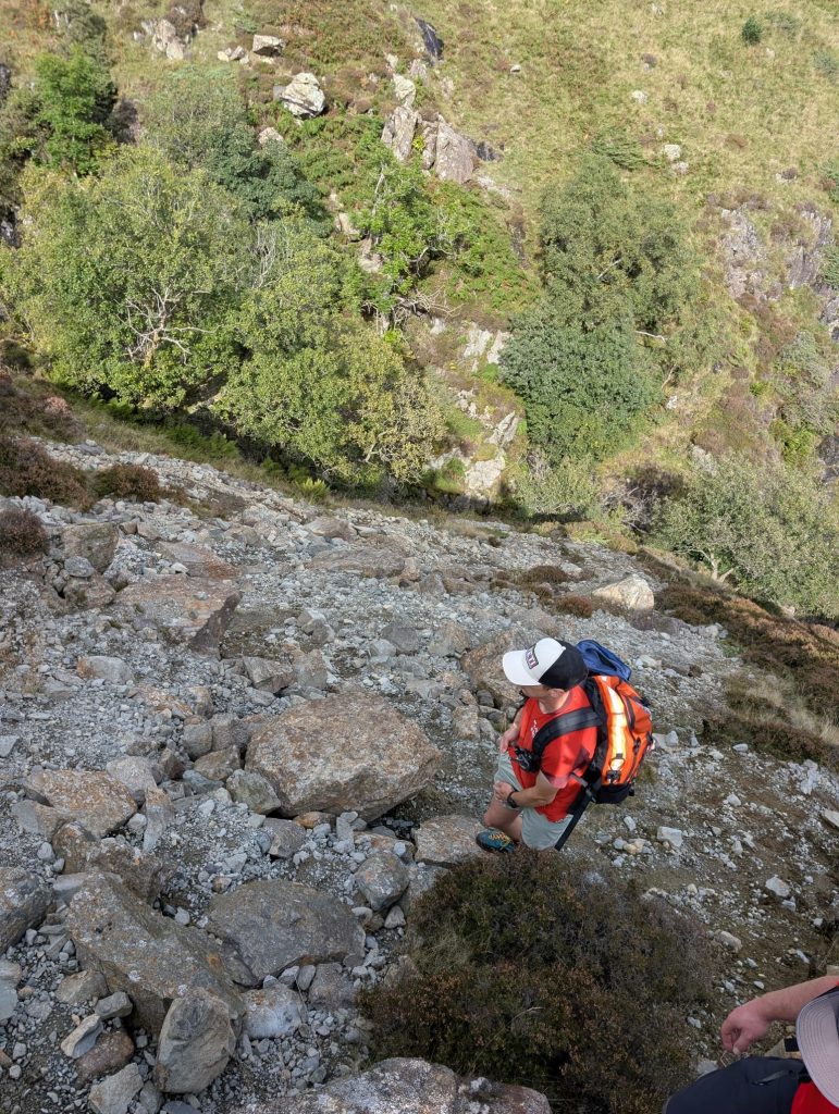 A team member picking a way across steep scree and boulders
