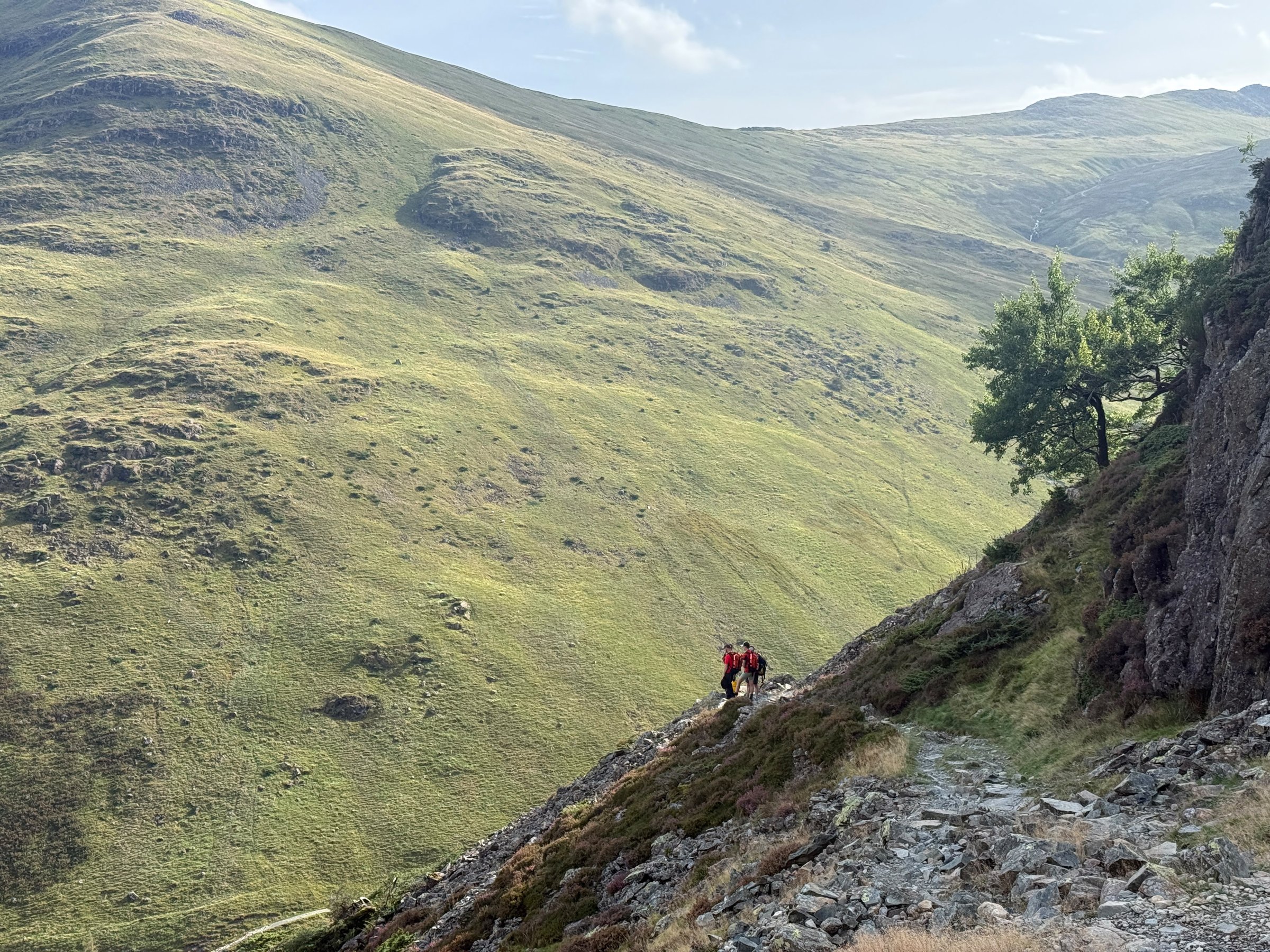 Two team members on a rocky path high above the Glenridding valley