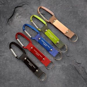 Five Patterdale Mountain Rescue Supporter carabiner key rings in black, red, blue, green and copper on slate